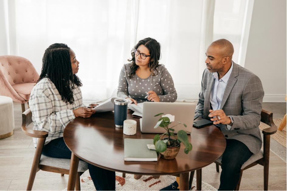 Three people sitting around a table having a meeting